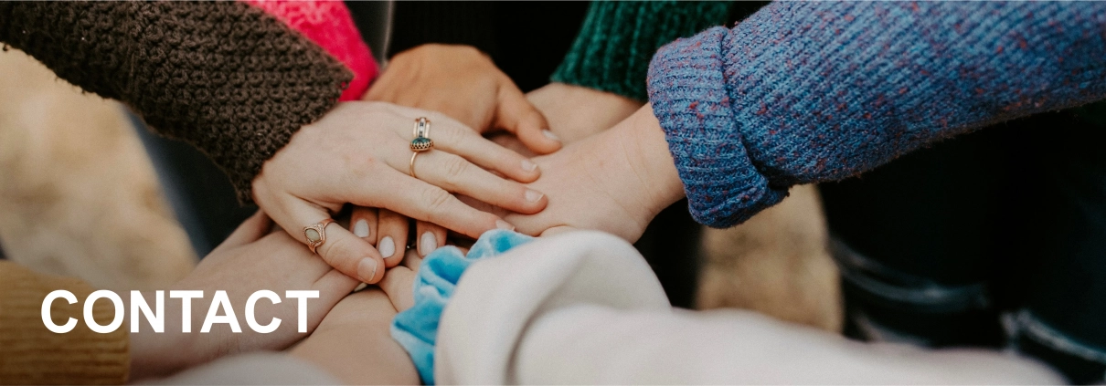 Several people stand in a circle and place their hands on top of each other in the middle.